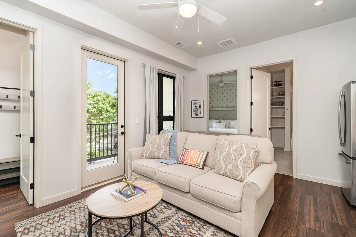 A bright and inviting living room with a sofa, coffee table, and a window offering a glimpse of the balcony. The setup is ideal for relaxation, conversation, and planning adventures, with decor that balances coziness and contemporary style.