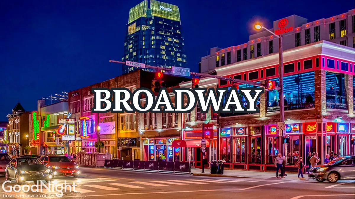 A vibrant exterior street scene with neon signs, crowded sidewalks, and cars, capturing the lively energy of Nashville’s famous Broadway area at night. The bustling atmosphere hints at live music, nightlife, and the street's reputation as an entertainment hotspot.