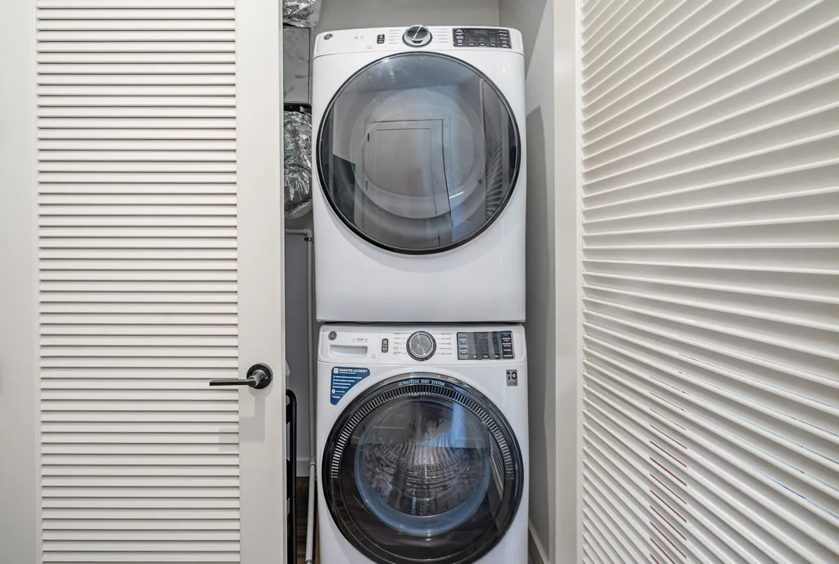 A dedicated laundry area featuring a washer and dryer behind a sliding door, with neatly organized laundry essentials and a sense of efficiency and order.