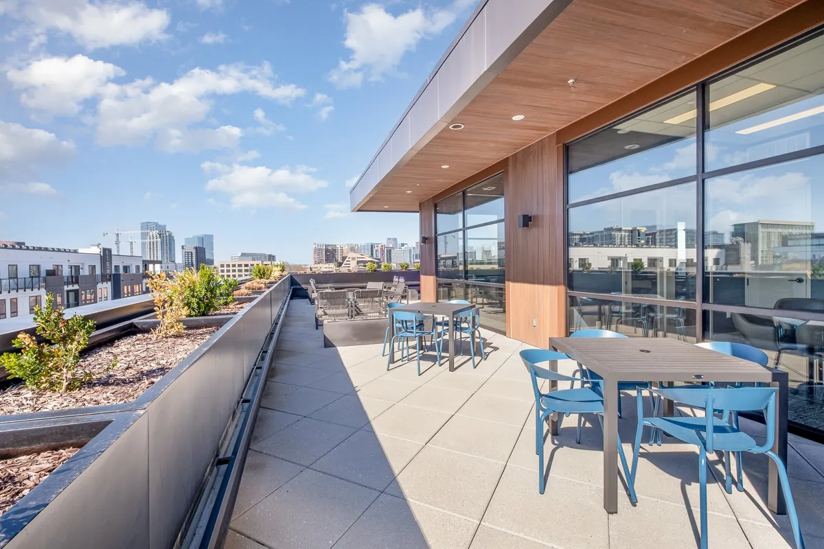 An inviting outdoor seating area with modern furniture and planters, set against the city skyline. The space is perfect for social gatherings, relaxing with friends, or enjoying sunset views after a day in the city.