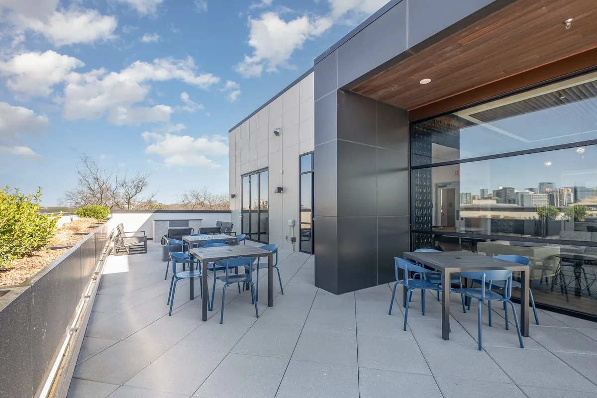 A stylish outdoor dining area with modern furniture, lush planters, and sweeping views of the city skyline. The space is designed for al fresco dining, social gatherings, or simply soaking up the Nashville ambiance.